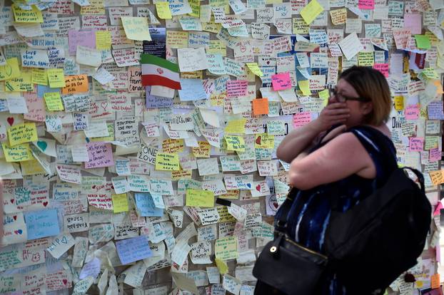 A woman reacts in front of a wall of messages in Borough Market, which officially re-opened today following the recent attack, in central London