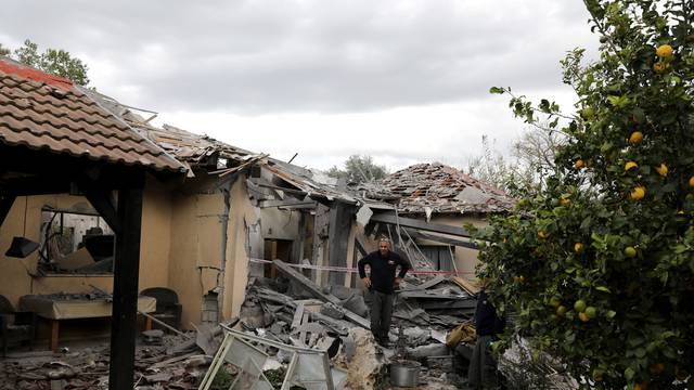 A police sapper inspects a damaged house that was hit by a rocket north of Tel Aviv Israel