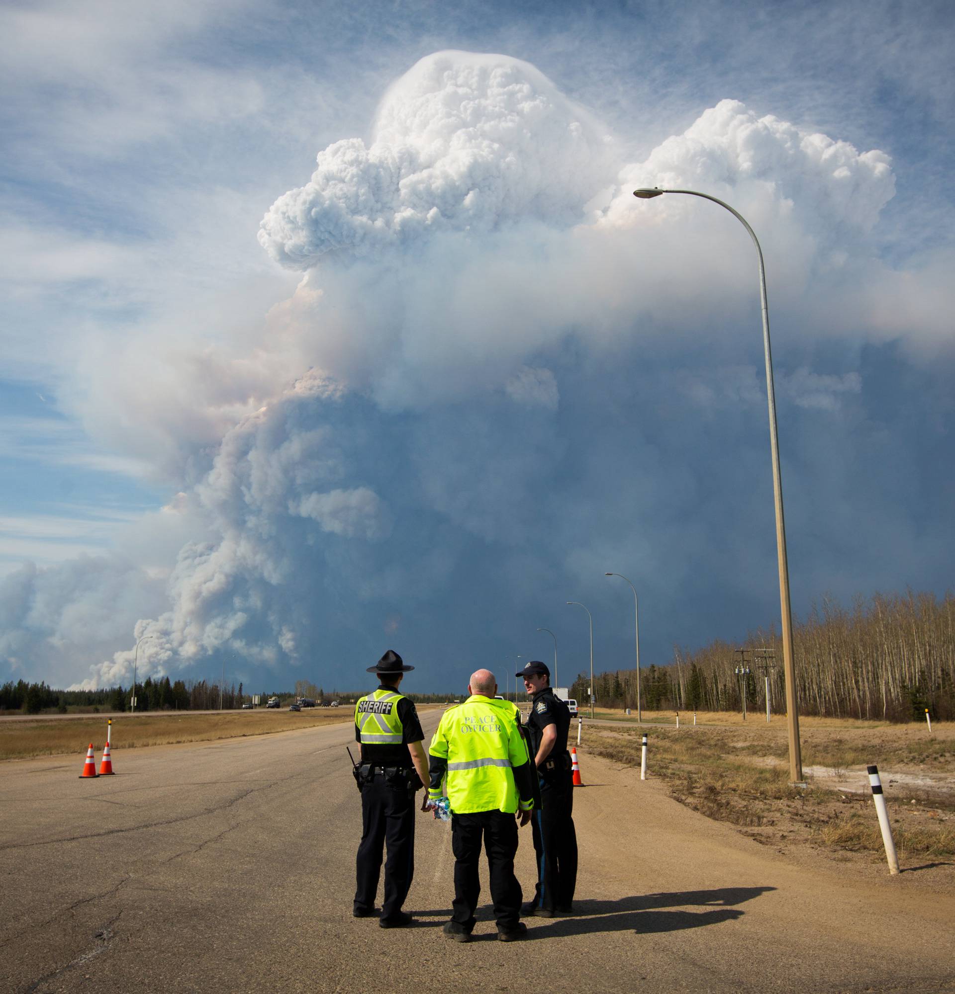 Officers look on as smoke from Fort McMurray's raging wildfires billow into the air after their city was evacuated