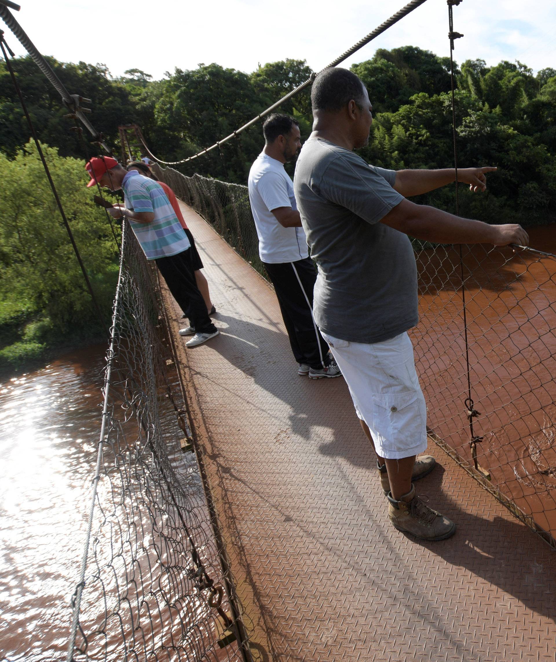 Residents stand on a bridge over mud-filled Paraopeba river, after a tailings dam owned by Brazilian mining company Vale SA collapsed, in Mario Campos near Brumadinho