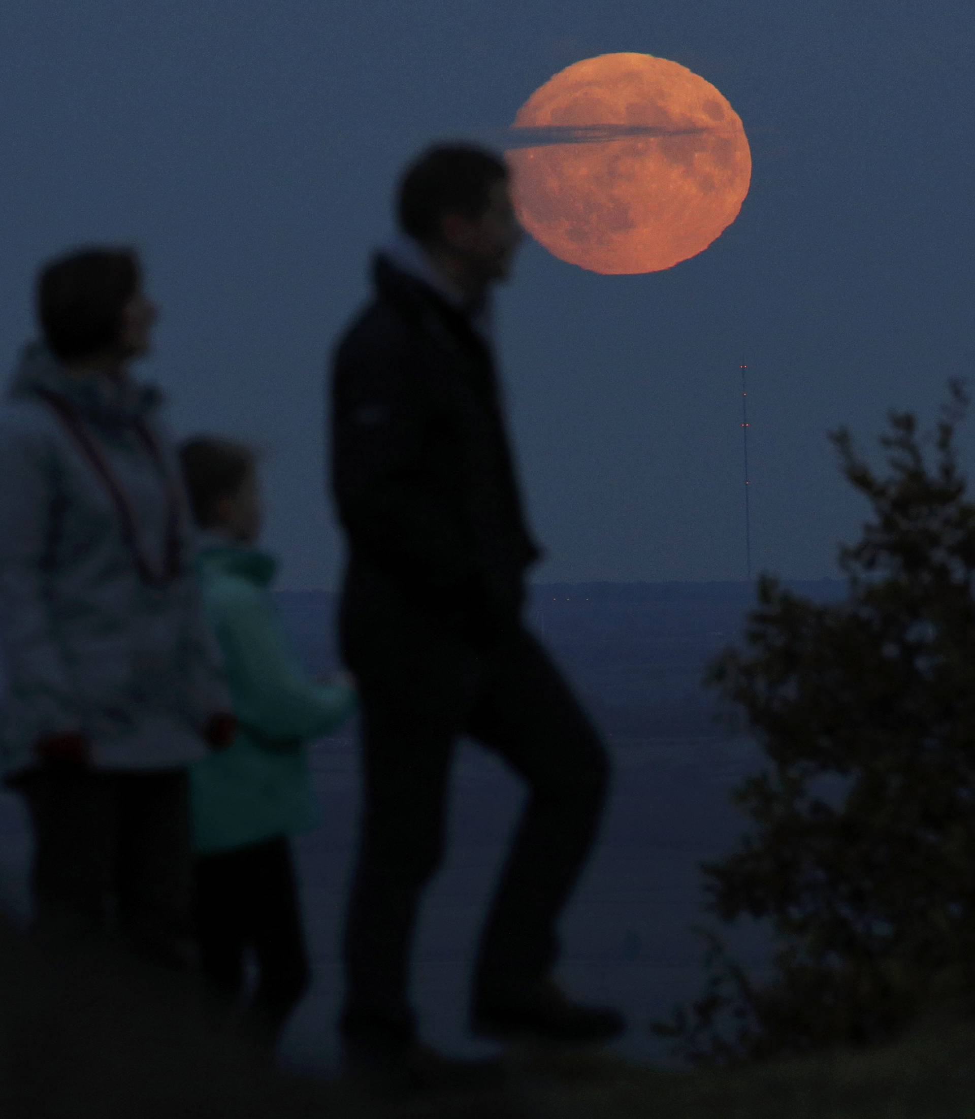 A family watch the moon rise a day before the "supermoon" spectacle on Beacon Hill near Loughborough