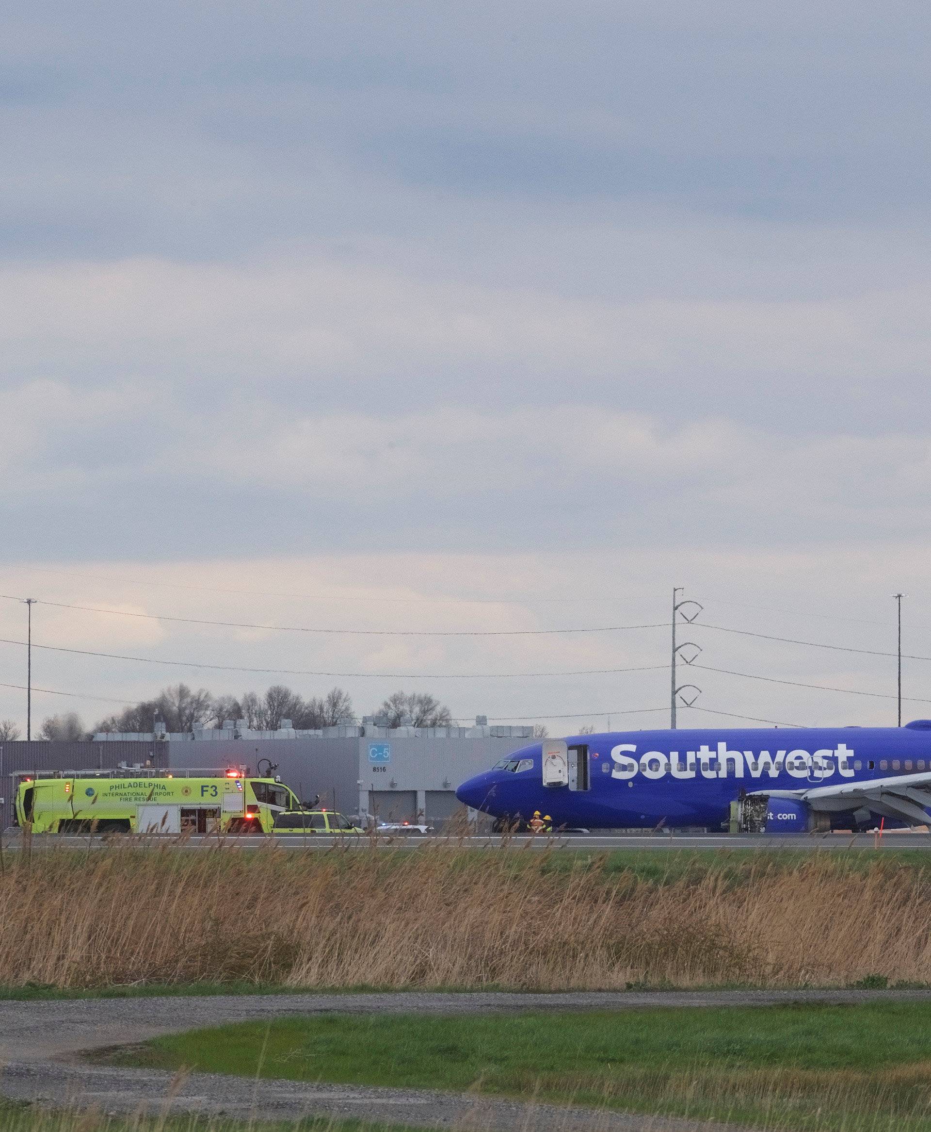 Emergency personnel monitor the damaged engine of Southwest Airlines Flight 1380, which diverted to the Philadelphia International Airport this morning, in Philadelphia, Pennsylvania