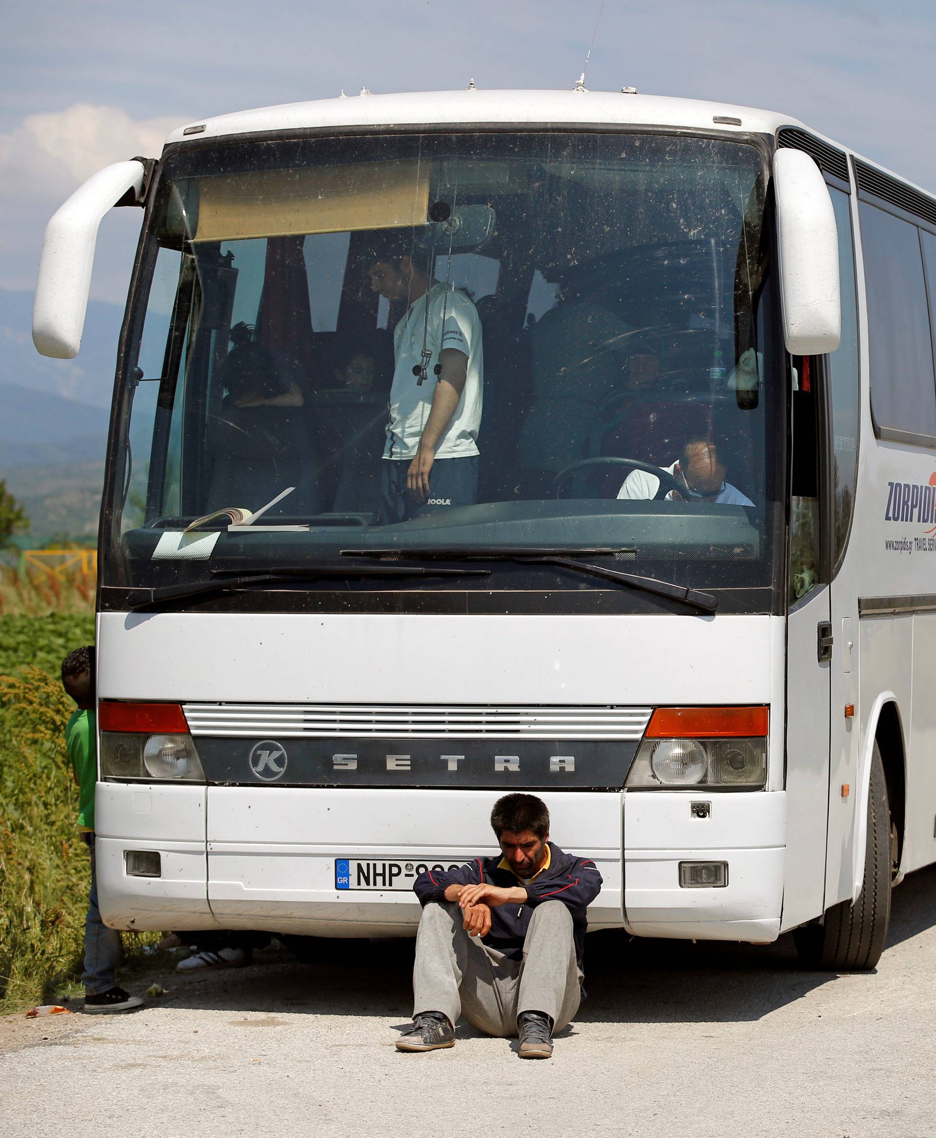 A migrant sits in front of a bus during a police operation to evacuate a migrants' makeshift camp at the Greek-Macedonian border near the village of Idomeni