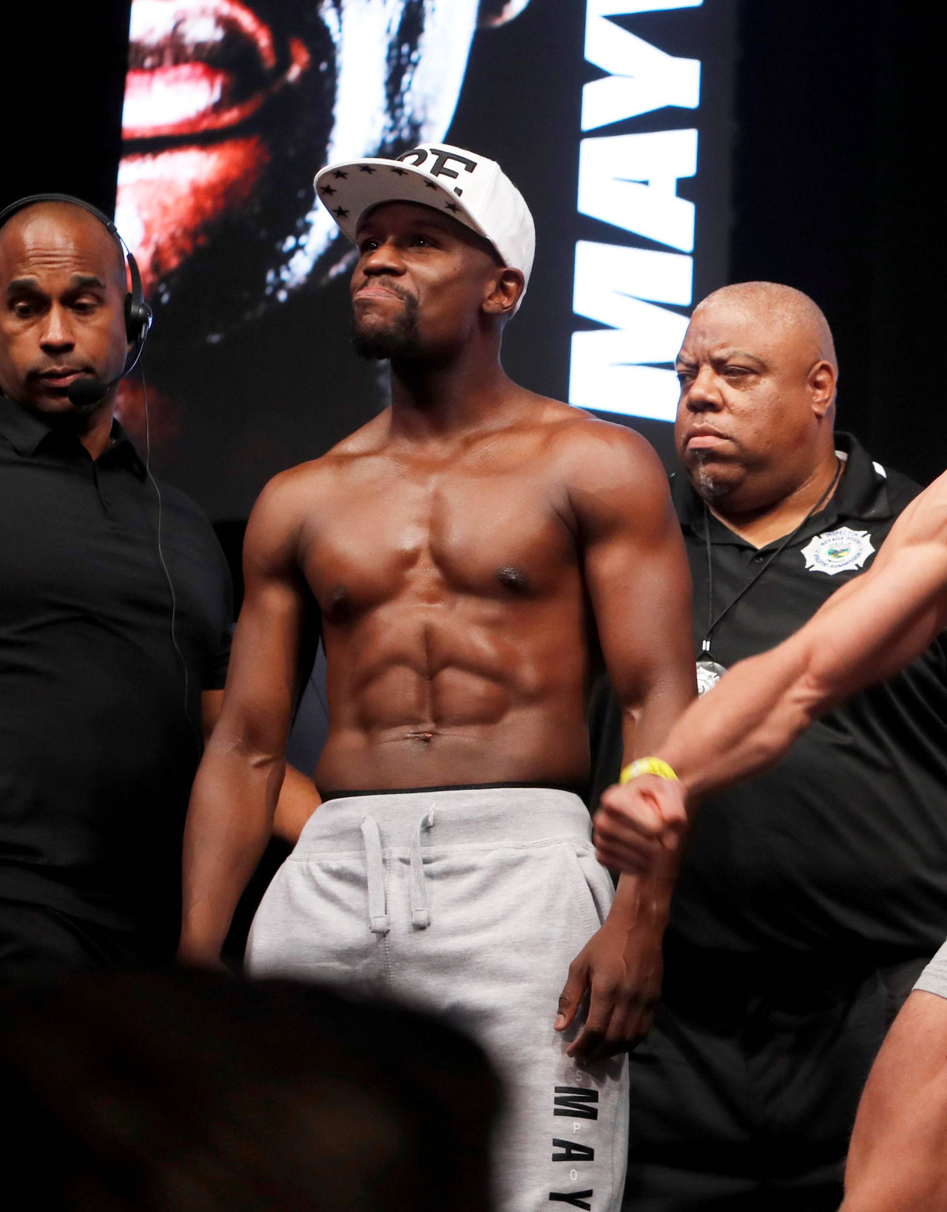 Undefeated boxer Floyd Mayweather Jr. (L) of the U.S. and UFC lightweight champion Conor McGregor of Ireland pose during their official weigh-in at T-Mobile Arena in Las Vegas
