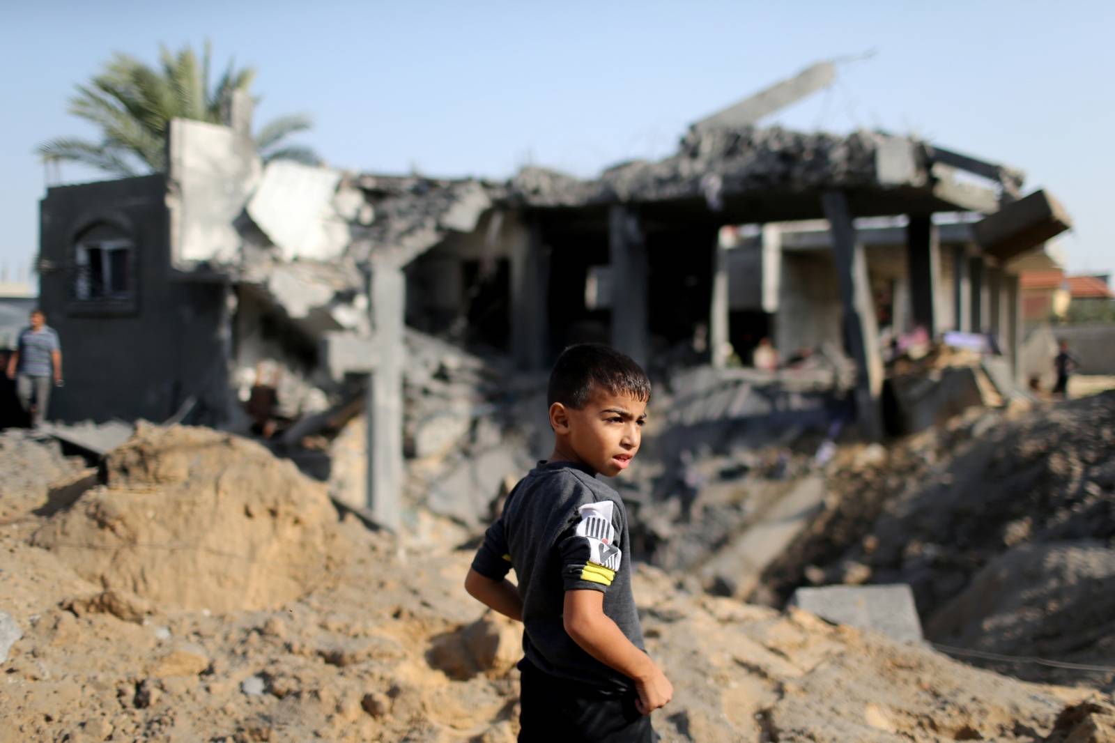 Palestinian boy looks on as he stands in front of the remains of a house destroyed in an Israeli air strike in the southern Gaza Strip