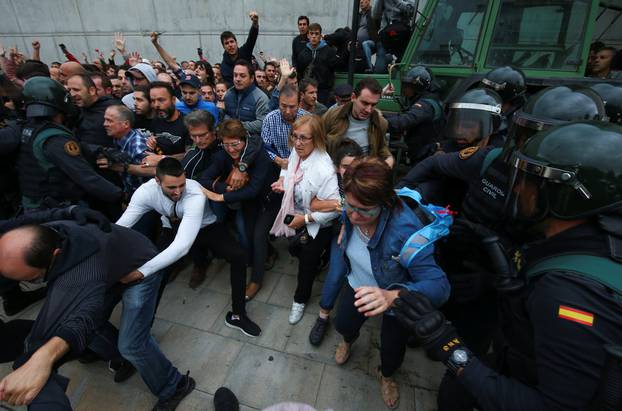 Spanish Civil Guard officers disperse people from the entrance of a polling station for the banned independence referendum in Sant Julia de Ramis