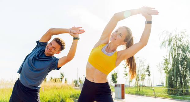 Couple,Stretching,Together,In,A,Sunny,Park,During,Morning,Exercise