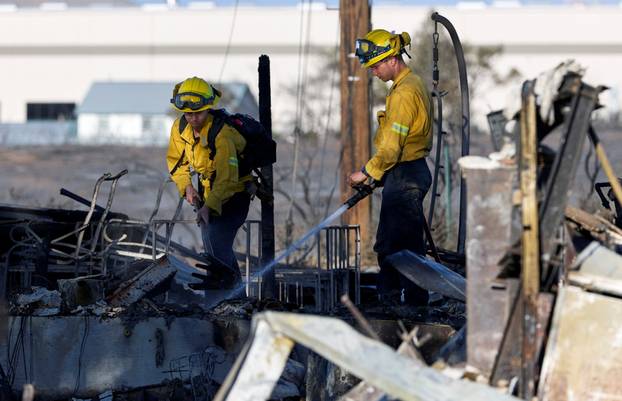 Two firefighters knock down hotspots at a burned home at Hawk Fire in Reno