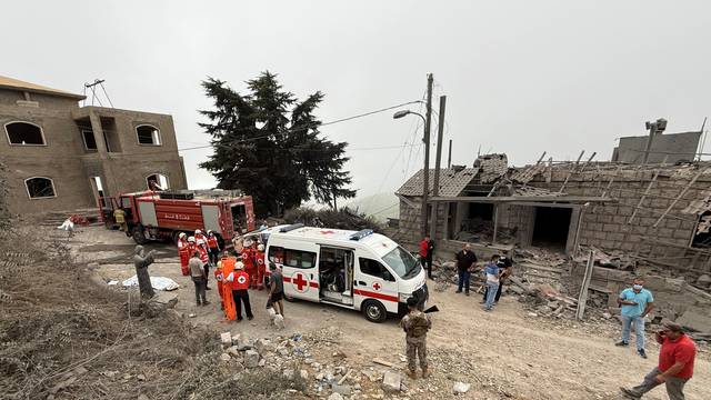 Lebanese Red Cross and Civil Defense vehicles are parked at a site damaged by an Israeli air strike in Aitou