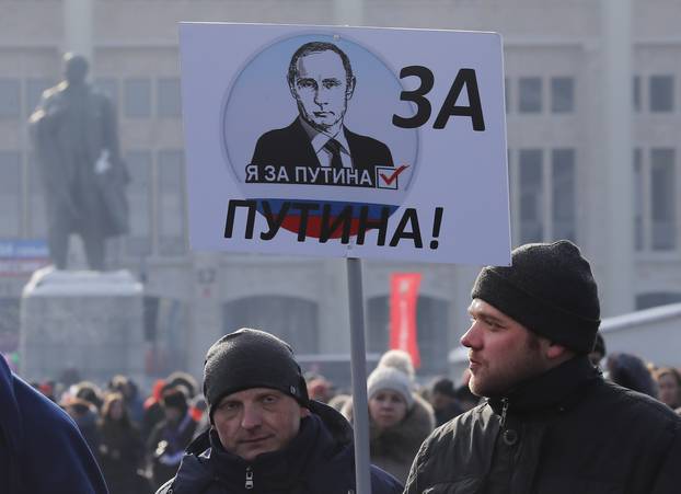 People carry a placard reading, "We are for Putin!" as they walk after a rally to support Russian President Putin in the upcoming presidential election at Luzhniki Stadium in Moscow