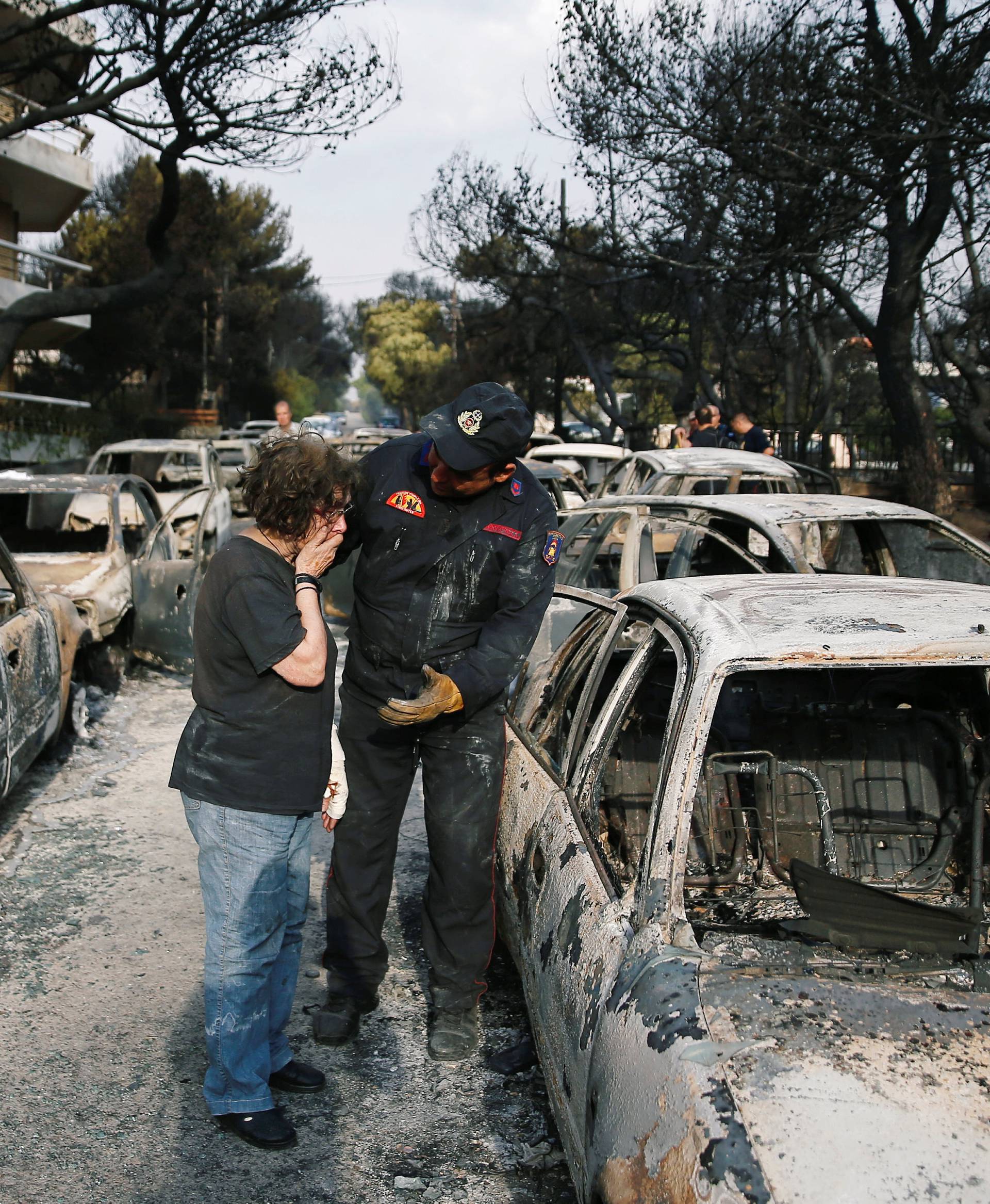 A woman reacts as she tries to find her dog, following a wildfire at the village of Mati, near Athens