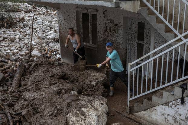 People clean debris following a landslide in the flooded village of Donja Jablanica