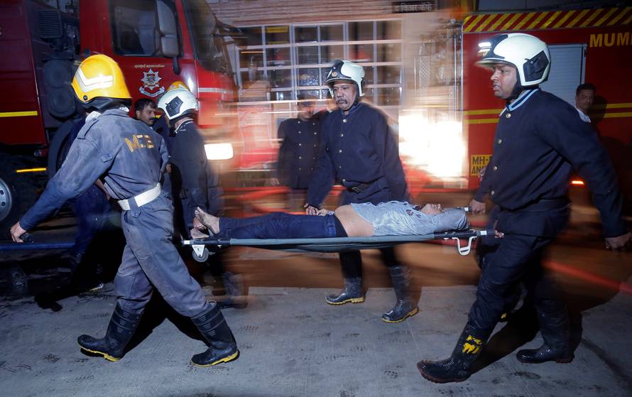 Firefighters carry a victim on a stretcher after a fire at a restaurant in Mumbai