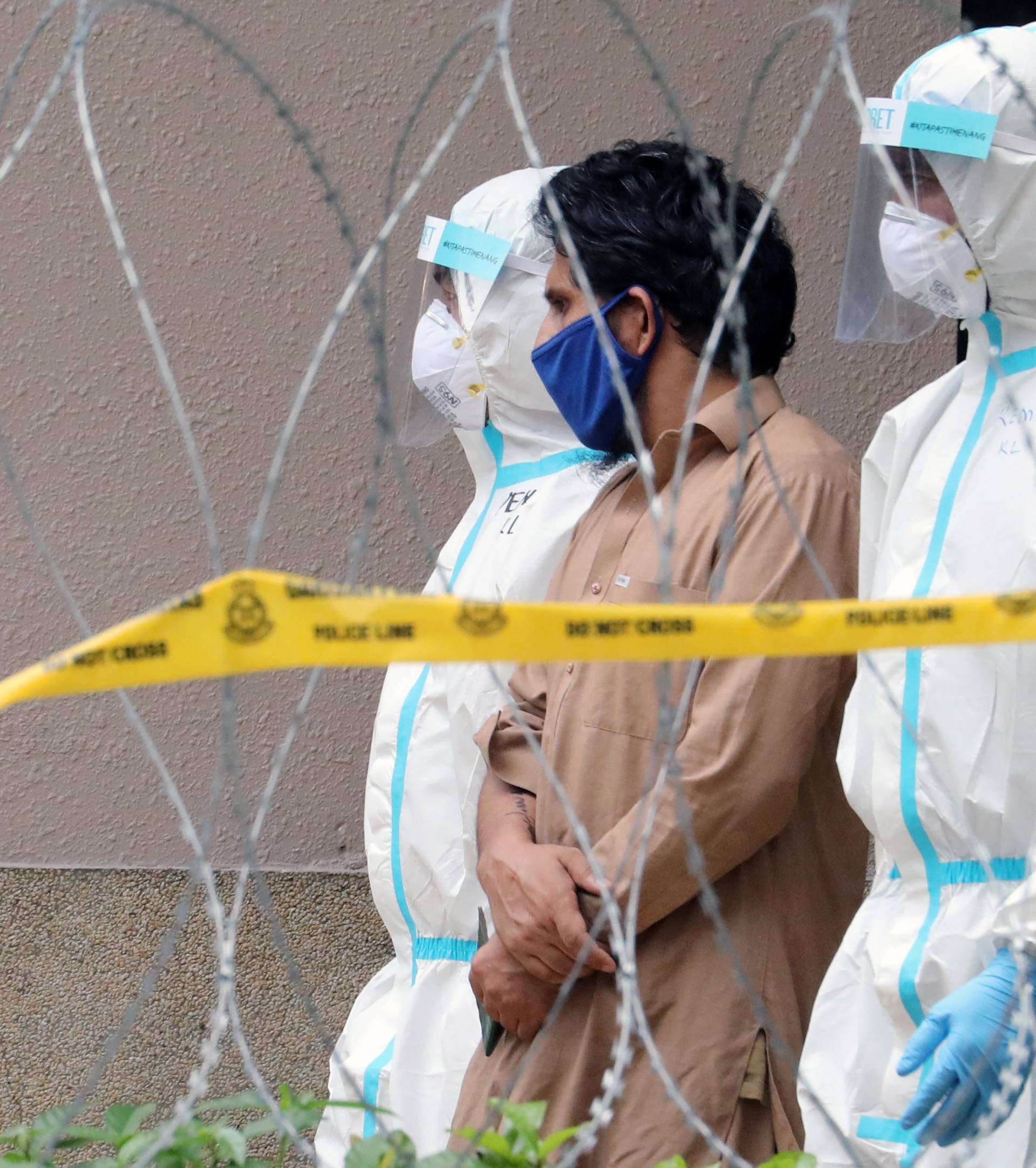 Police officers wearing protective suits pick up an illegal immigrant from an apartment under enhanced lockdown, during the movement control order due to the outbreak of the coronavirus disease (COVID-19), in Kuala Lumpur