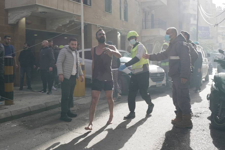 A man runs along a street among members of the Lebanese Civil Defence and civilians following an Israeli air strike in Beirut