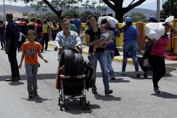 A woman carries tires on a baby stroller while she crosses to Venezuela over the Simon Bolivar international bridge after shopping in Cucuta