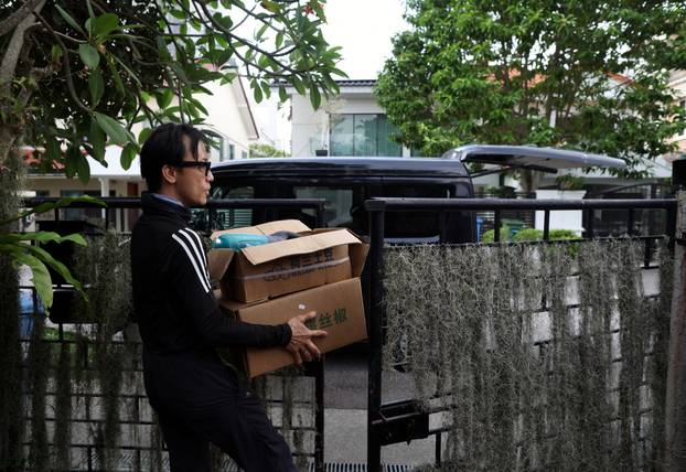 Bee rescuer Clarence Chua leaves a house with a box of bees he had removed, in Singapore