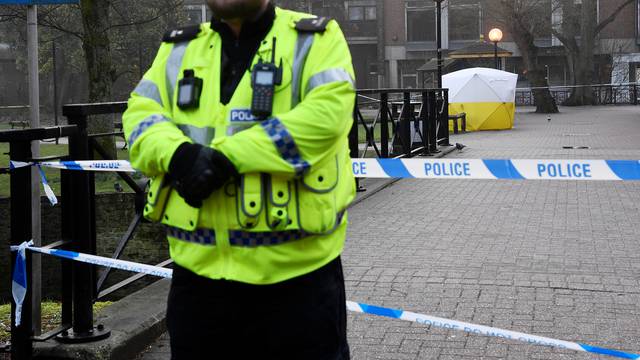 Police officers stand at crime scene tape, as a tent covers a park bench on which former Russian inteligence officer Sergei Skripal, and a woman were found unconscious after they had been exposed to an unknown substance, in Salisbury
