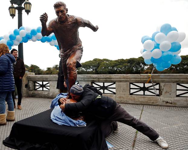 A man grabs and kisses the statue of Argentina