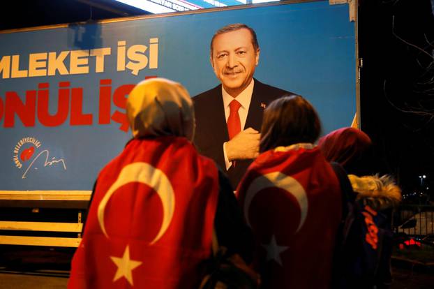 Supporters of AK Party stand in front of a billboard picturing Turkish President Tayyip Erdogan, in Istanbul