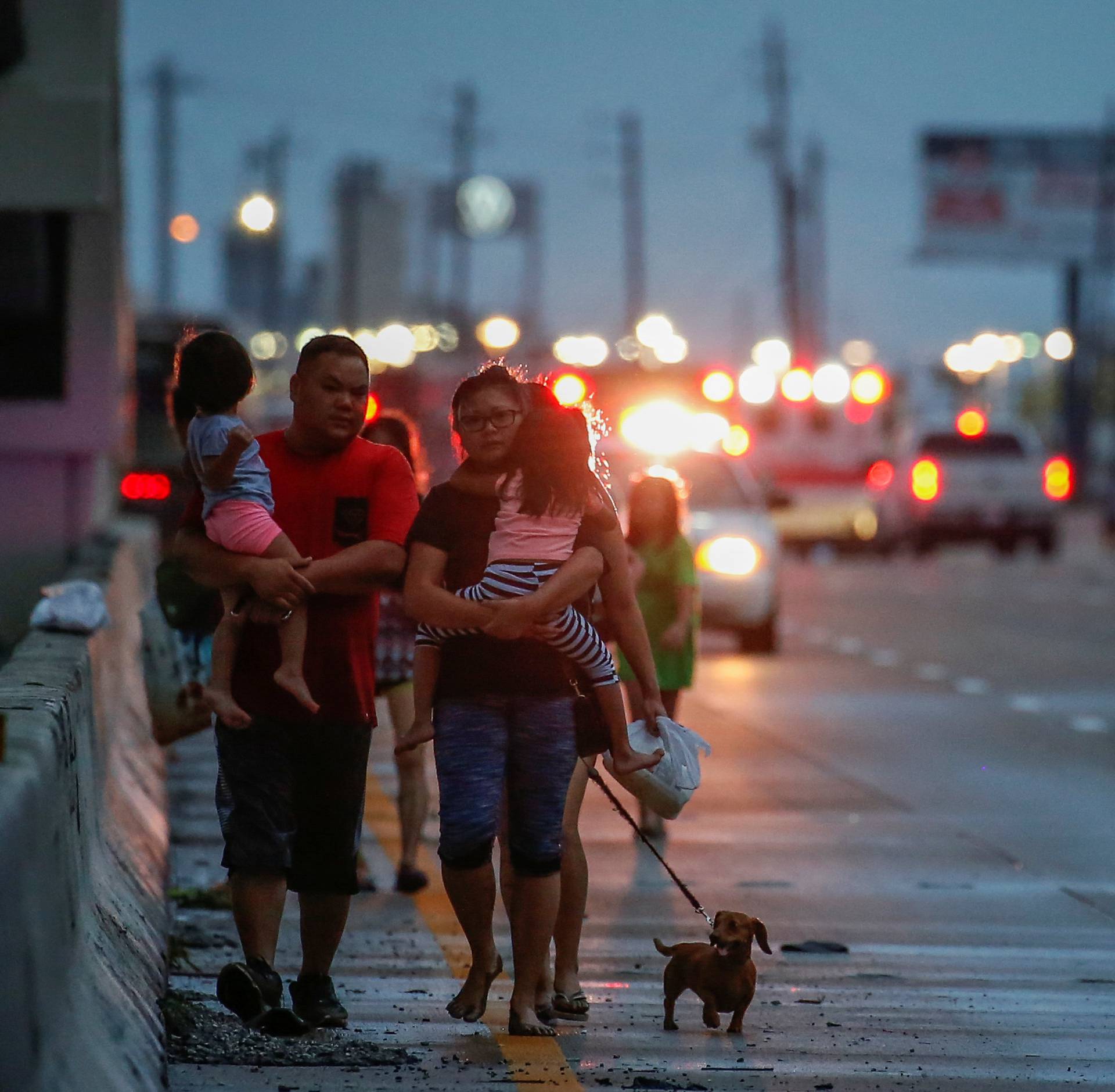 The Duong family, with children, parents and dog in tow, walks along Interstate 45 while escaping flood waters from Tropical Storm Harvey in Houston