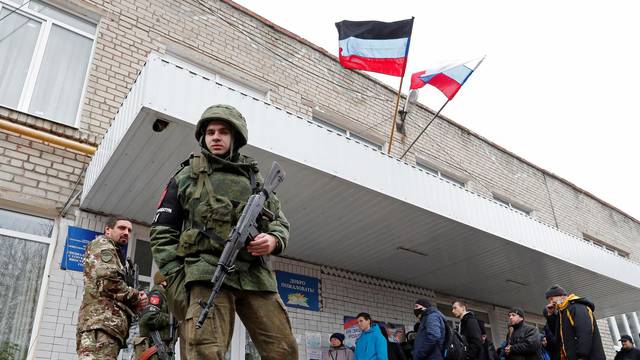 Militants of the self-proclaimed Donetsk People's Republic stand outside a military mobilization point in the separatist-controlled city of Donetsk