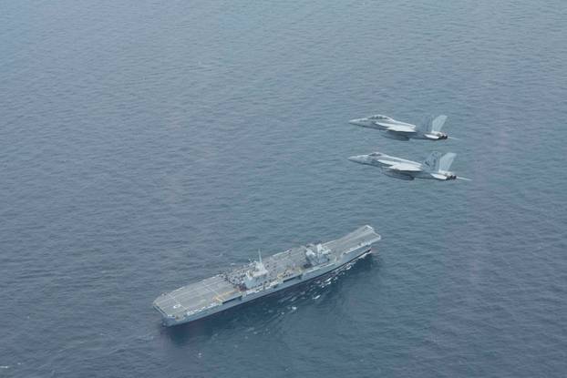 U.S. Navy F/A-18E and F/A-18F Super Hornets fly in formation above the Royal Navy aircraft carrier HMS Queen Elizabeth during exercise Saxon Warrior in the Atlantic Ocrean