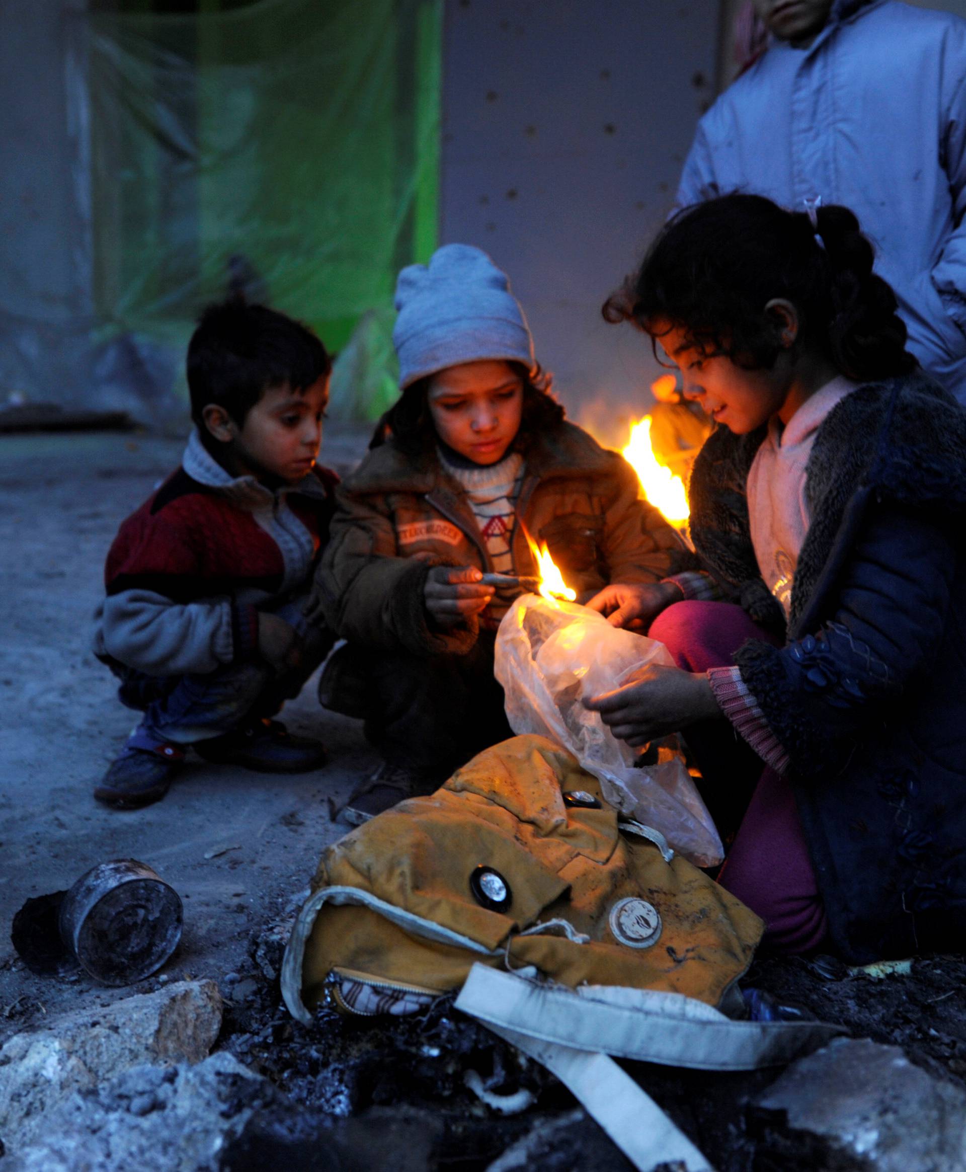 Syrians evacuated from eastern Aleppo, light a fire using plastic bags to keep warm, inside a shelter in government controlled Jibreen area in Aleppo