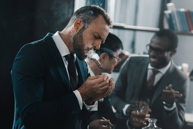 businessman smoking cigar with multicultural business team