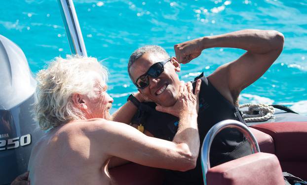 Former U.S. President Barack Obama and British businessman Richard Branson sit on a boat during Obama