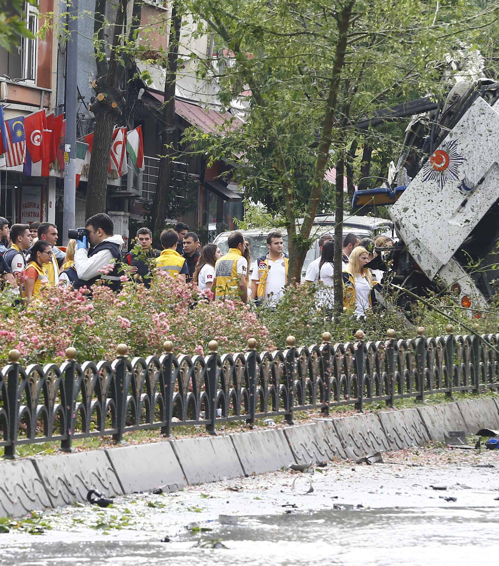 People stand beside beside a Turkish police bus which was targeted in a bomb attack in a central Istanbul district