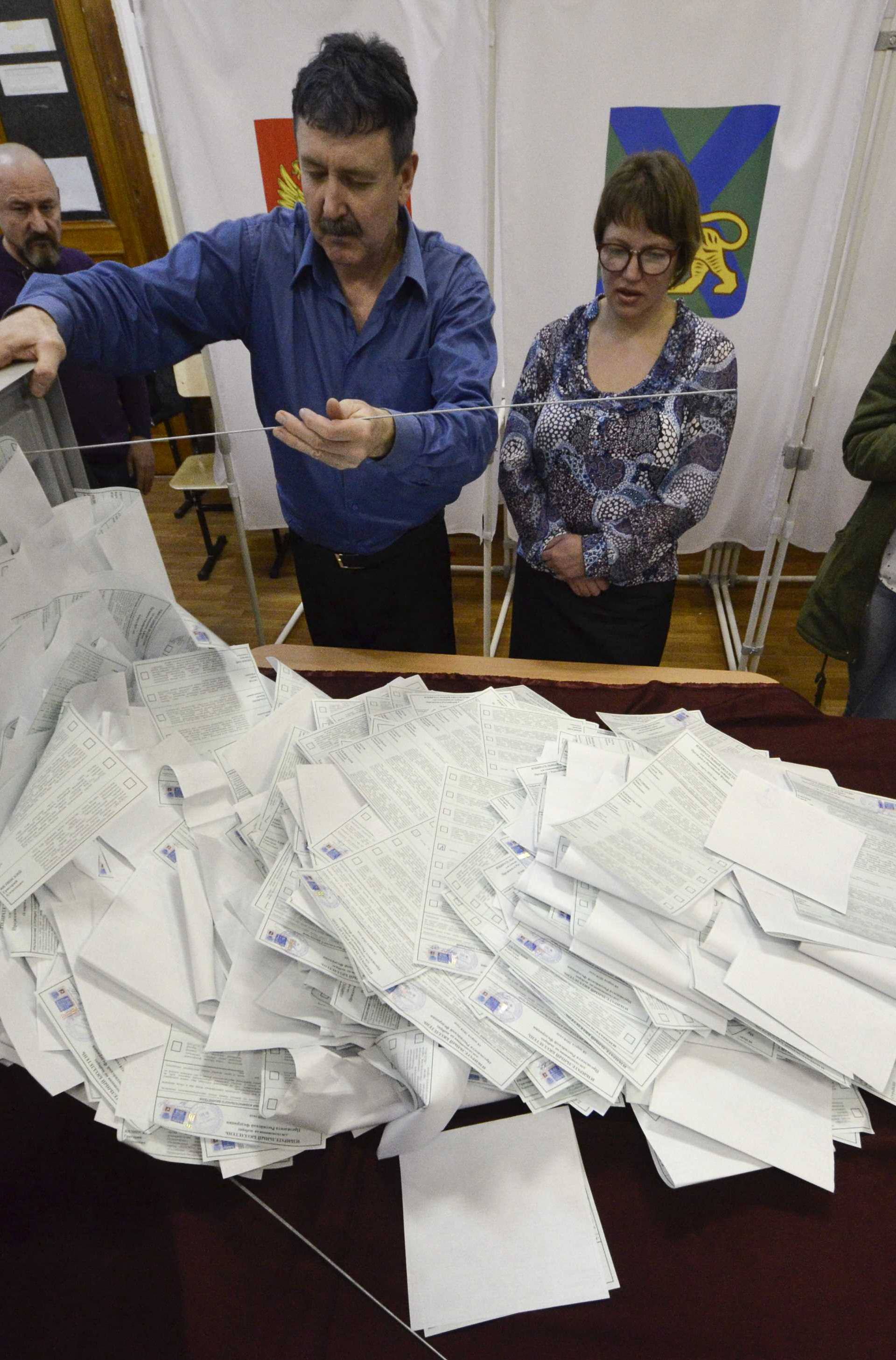 Members of a local election commission empty a ballot box before starting to count votes during the presidential election in Vladivostok