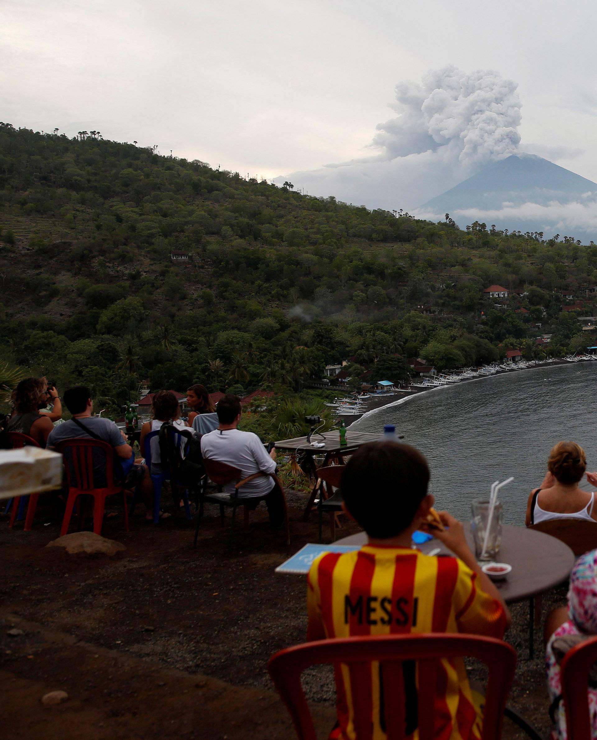 People watch Mount Agung volcano erupt from a cafe near Amed, Karangasem Regency, Bali