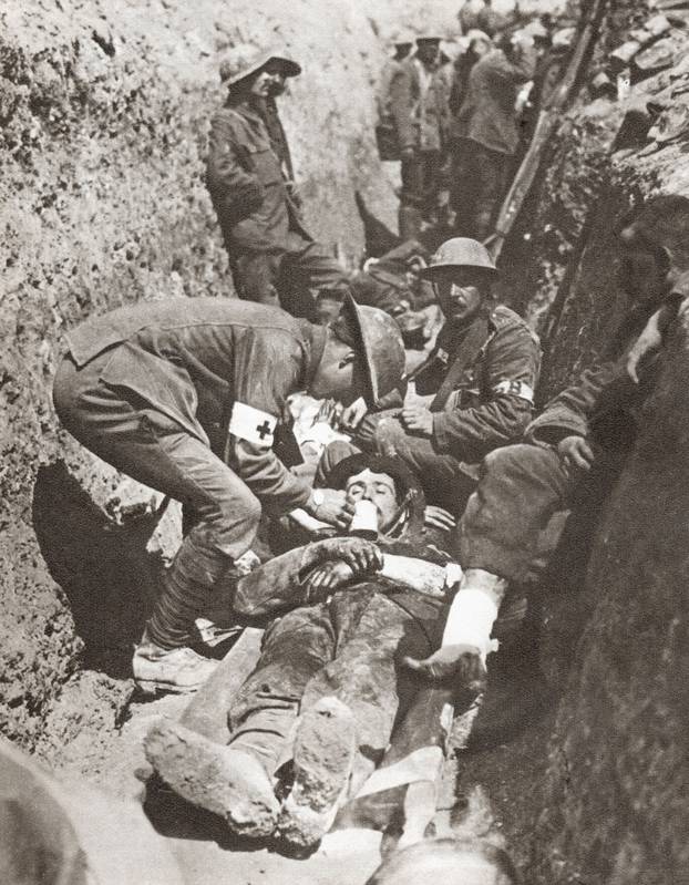 Stretcher bearers giving aid to a soldier lying wounded in a trench on The Somme, France during World War I.