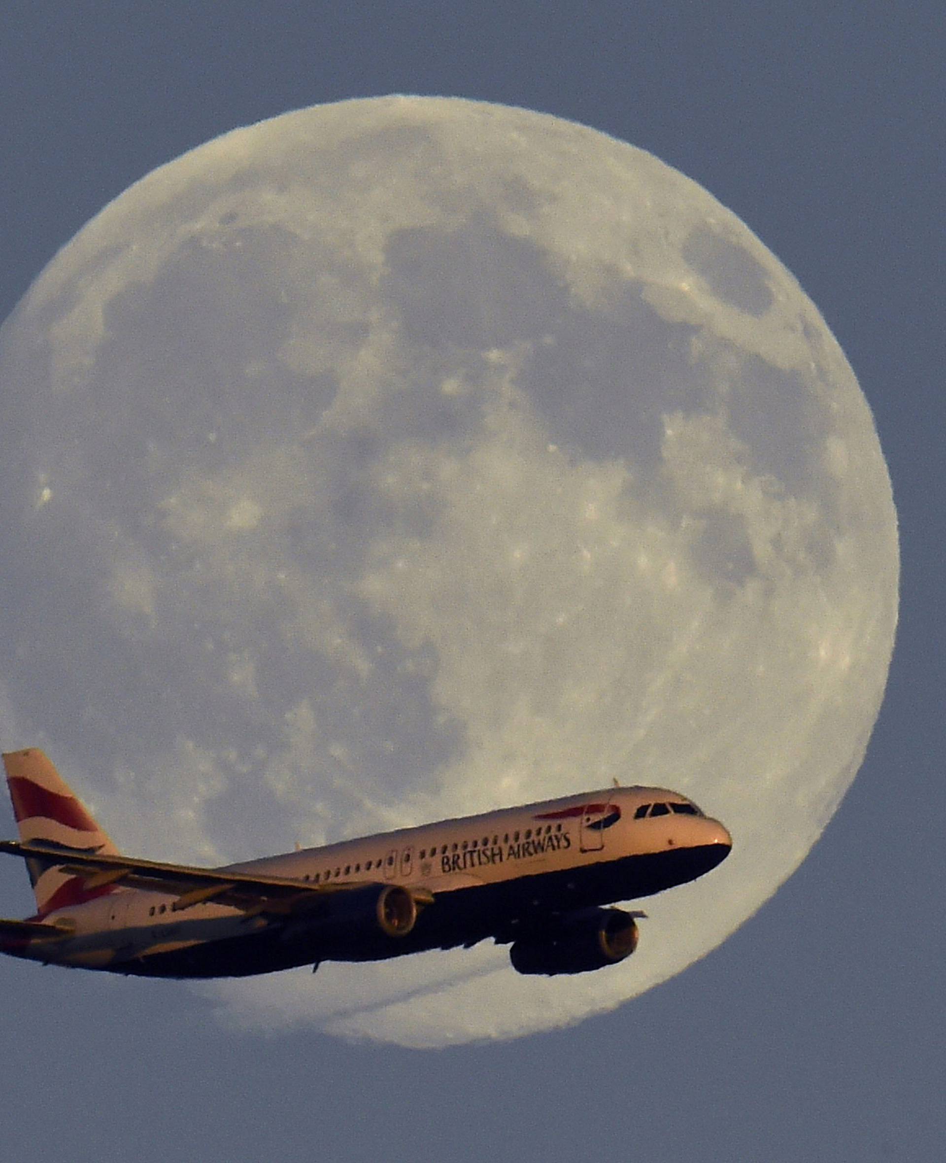 A British Airways passenger aircraft passes in front of the moon as it makes it's landing approach towards Heathrow Airport in west London in this photograph taken on July 18, 2016.