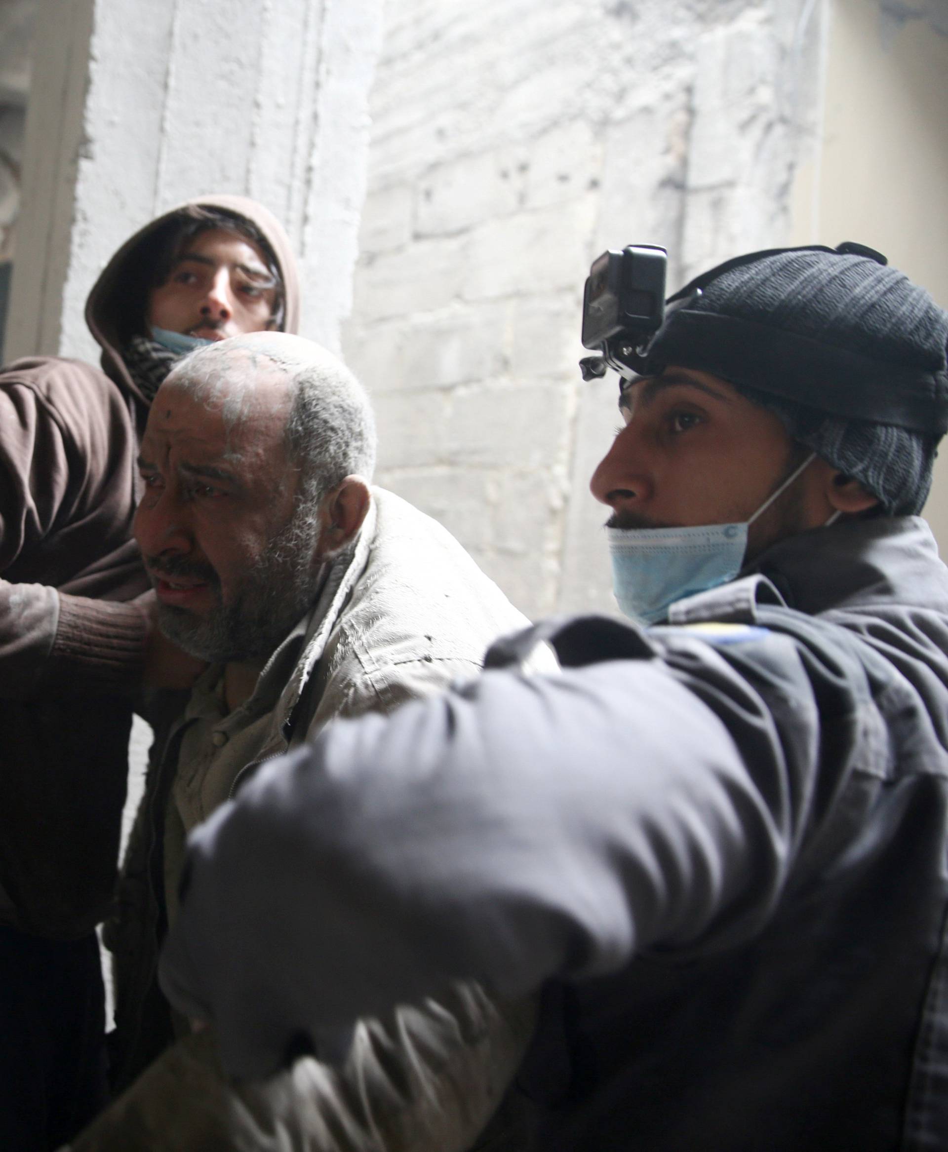 Civil defence help a man from a shelter in the besieged town of Douma