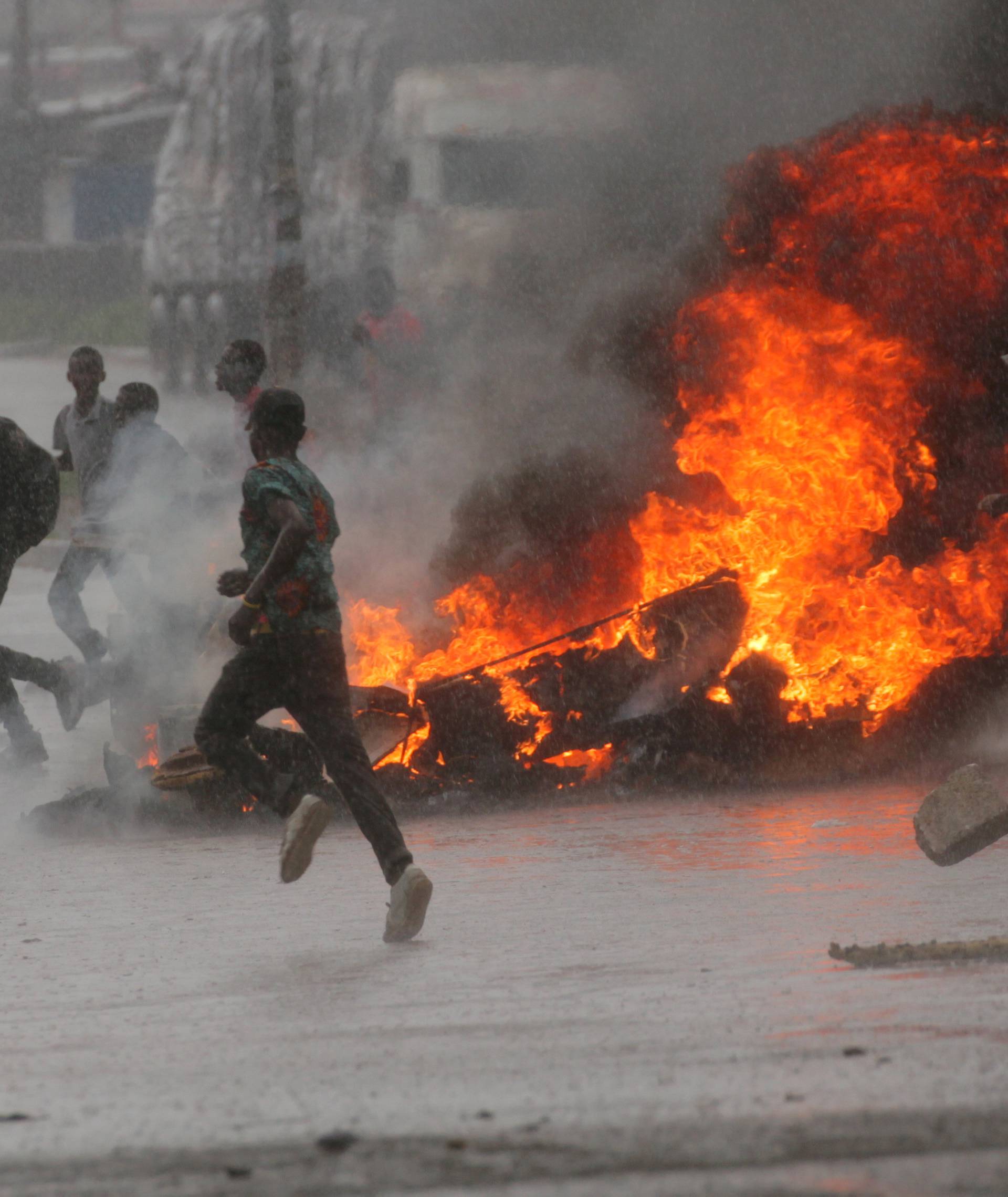 People run at protest as barricades burn during rainfall in Harare