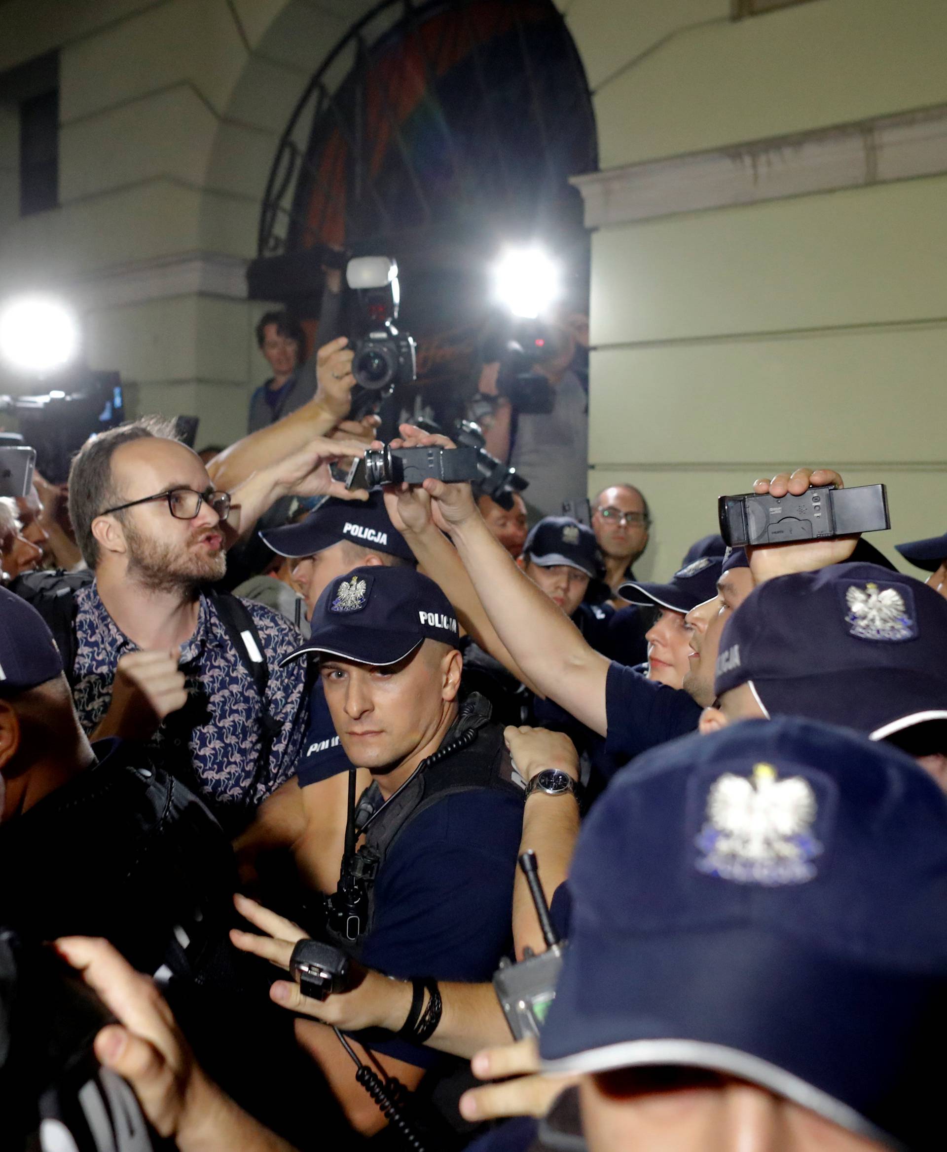 A man chants slogans next to police officers during the "Chain of lights" protest against judicial overhaul in front of the Presidential Palace in Warsaw