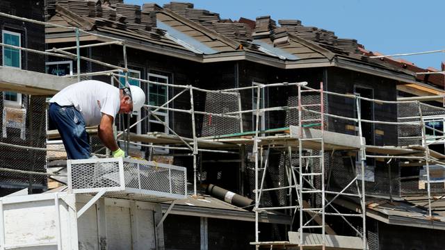 A construction worker is shown building luxury single family homes in Carlsbad, California