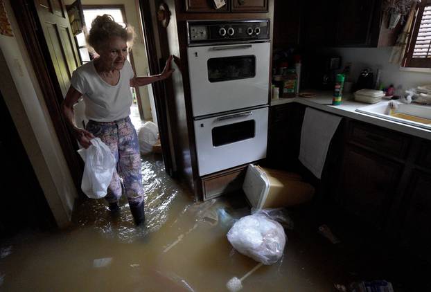 Nancy McBride collects items from her flooded kitchen as she returned to her home for the first time since Harvey floodwaters arrived in Houston