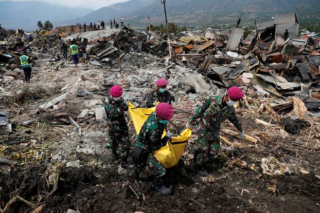 Indonesian soldiers carry a dead body from the ruins of houses after an earthquake hit Balaroa sub-district in Palu