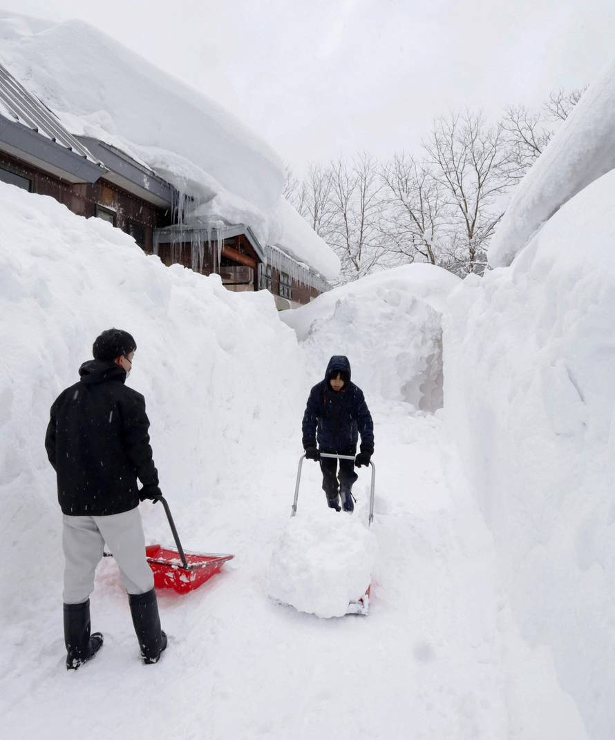 People remove snow near a house in Aomori, northeastern Japan, as heavy snow continues to hit the region