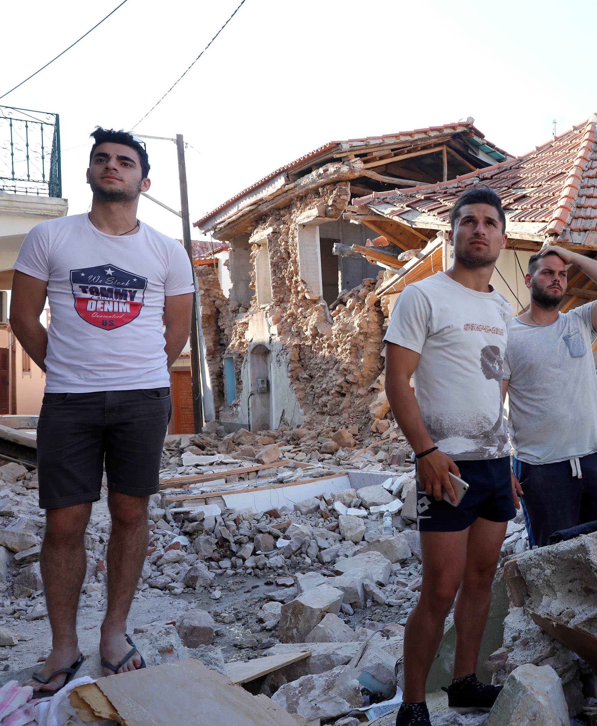 People stand among damaged buildings at the village of Vrissa on the Greek island of Lesbos, Greece, after a strong earthquake shook the eastern Aegean