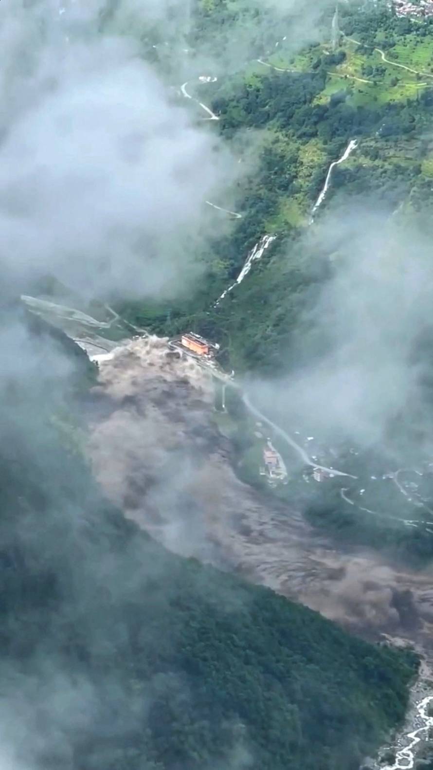An overflowing river floods buildings and roads near Betrawati Bazaar, Uttargaya municipality
