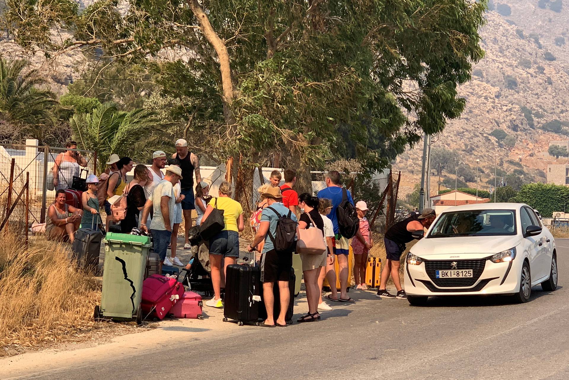 Tourists are being evacuated as wildfire burns near Lindos on the island of Rhodes