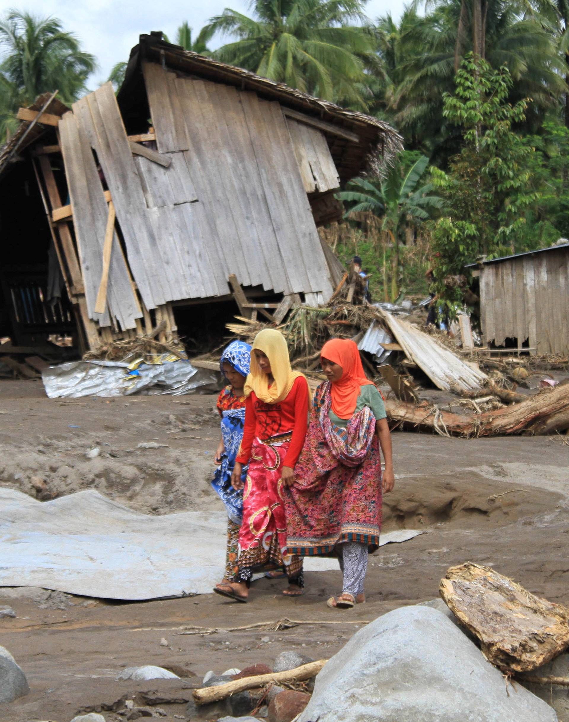 Residents walk in a village devastated by flashfloods in Salvador, Lanao del Norte