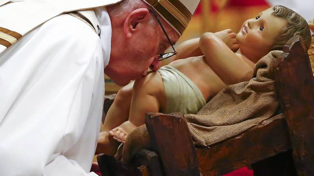 Pope Francis kisses a statue of baby Jesus at the end of the Christmas night Mass in Saint Peter's Basilica at the Vatican