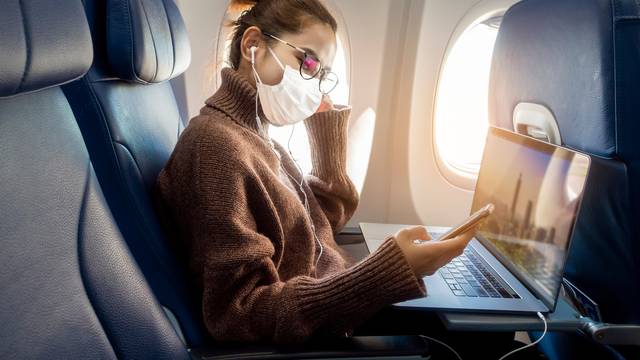 A,Young,Woman,Wearing,Face,Mask,Is,Traveling,On,Airplane