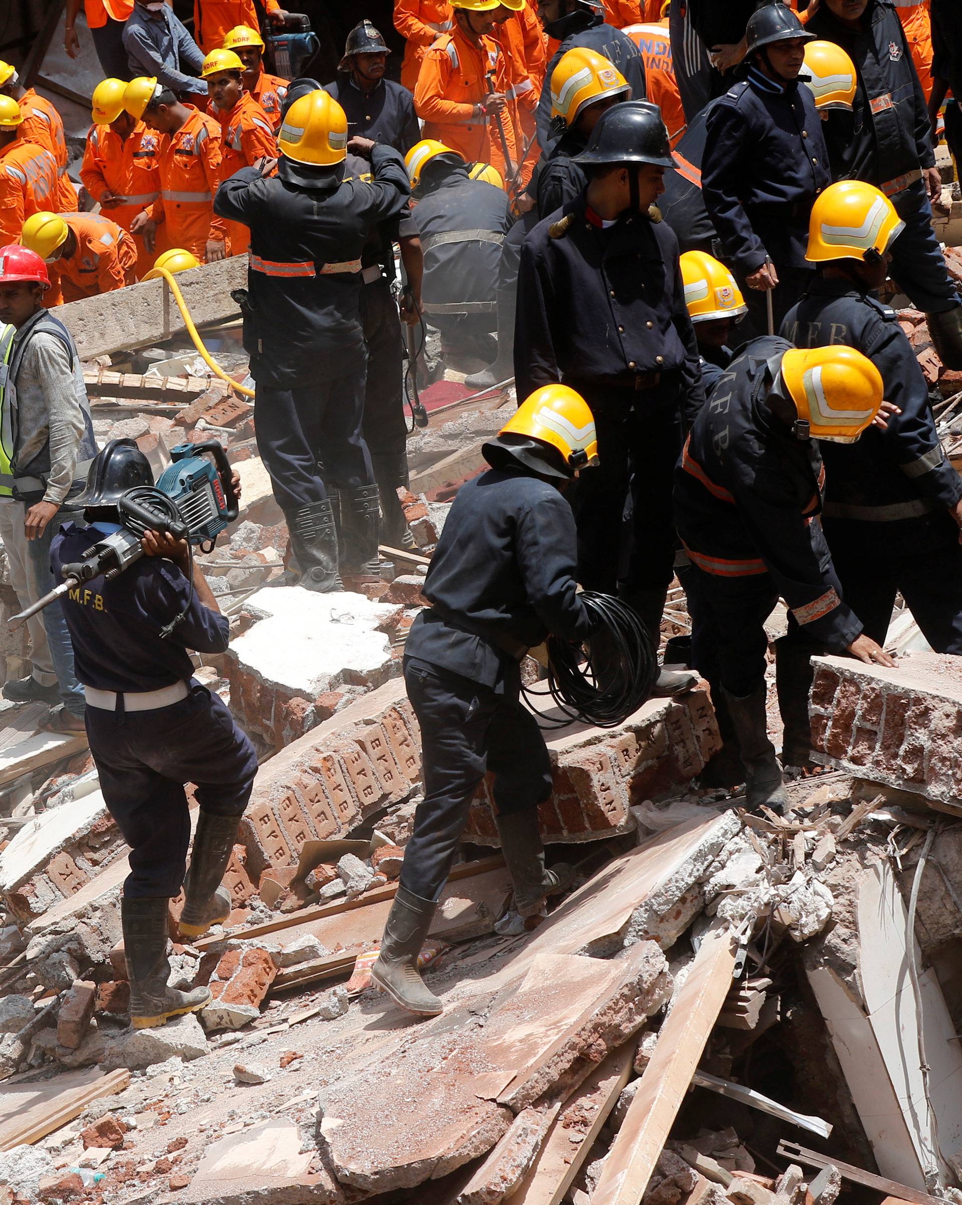 A firefighter arrives with a jack-hammer during a search for survivors at the site of a collapsed building in Mumbai