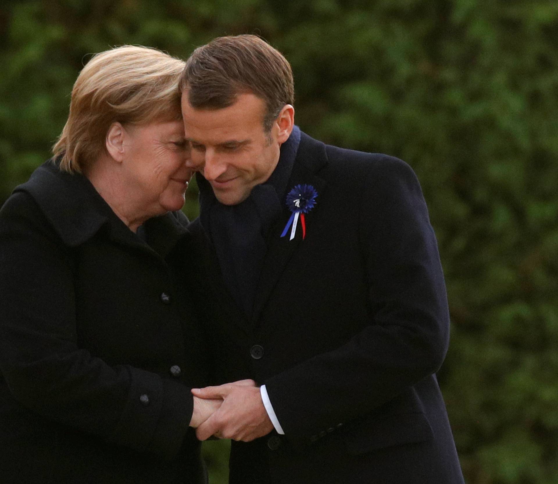 French President Emmanuel Macron and German Chancellor Angela Merkel hug after unveiling a plaque in the Clairiere of Rethondes during a commemoration ceremony for Armistice Day, 100 years after the end of the First World War, in Compiegne